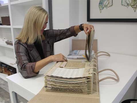 A woman with light hair, looking at fabric samples